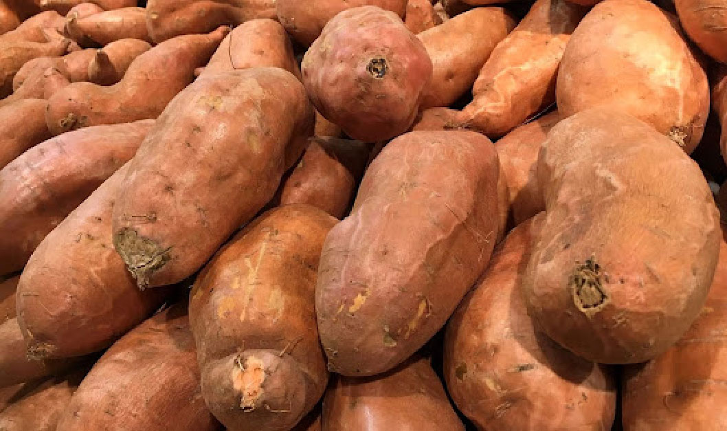 A close up shot of sweet potatos piled on top of eachother | In-season Produce